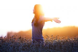 Young woman enjoying nature and sunlight in wheat field.